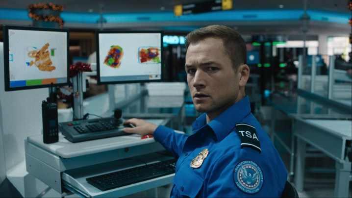Taron Egerton assis à un bureau se retournant dans Carry-On.