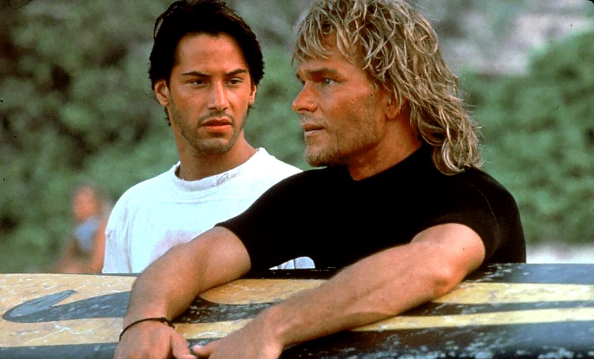 Un homme regarde un autre homme tenant une planche de surf devant lui