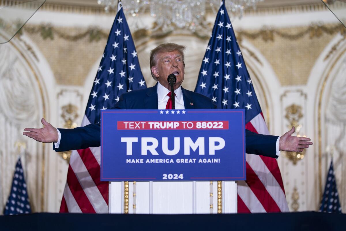 Donald Trump élu président se tenant à un podium, drapeaux américains derrière lui, à sa résidence Mar-a-Lago en 2023.