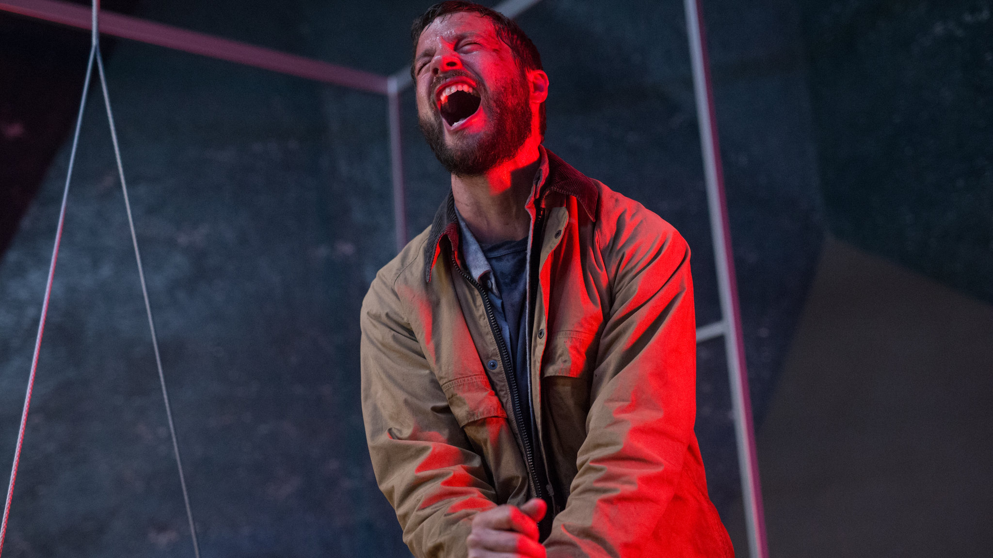 Un homme baigné dans une lumière rouge hurlant de douleur dans Upgrade.