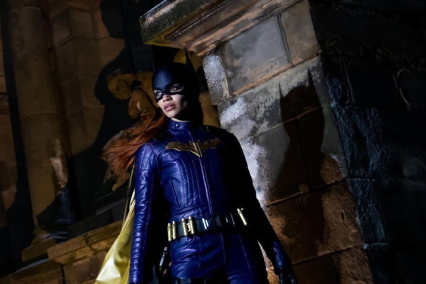 Batgirl se tient solennellement à côté d'un pilier de pierre, projetant une ombre dessus.