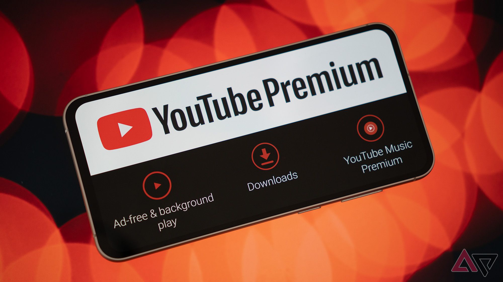 Un téléphone affichant le logo de YouTube Premium et ses fonctionnalités sur un fond flou rouge.