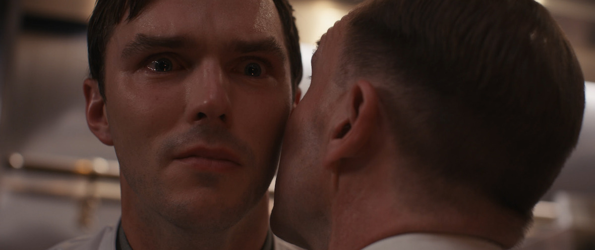 Un homme chuchote à l'oreille de Nicholas Hoult dans le film 'The Menu'.