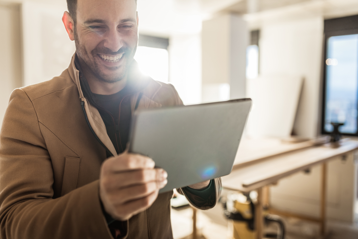 Personne tenant une tablette avec un sourire.