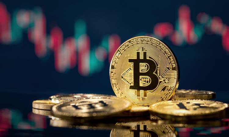 Pièce Bitcoin dorée devant un graphique boursier flou