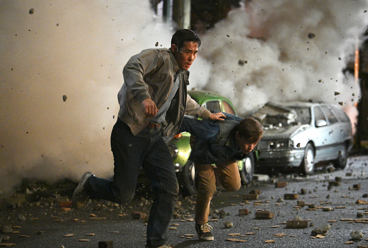 Raymond Lee dans le rôle du Dr Ben Song et Everett Andres dans celui de Jason fuient un bâtiment en effondrement.