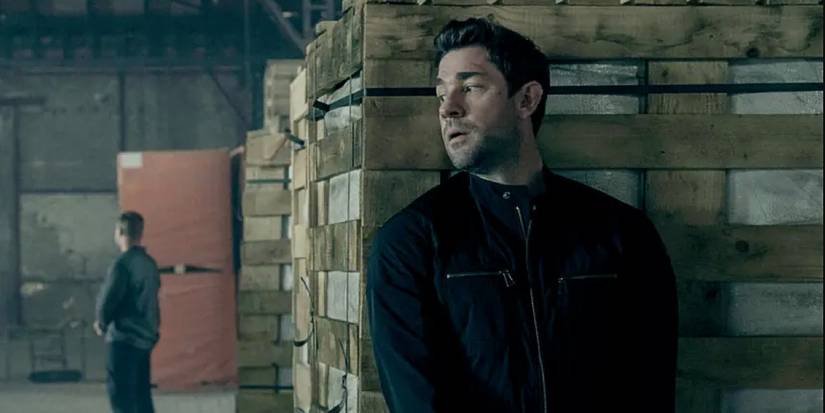 John Krasinski as Jack Ryan hiding behind a box in Jack Ryan season 3.