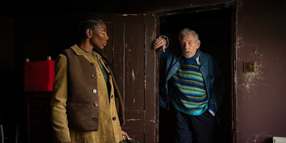 Michaela Cole (à gauche), une femme noire portant des vêtements d'automne, se tient près d'Ian McKellen, un homme blanc barbu également vêtu de couches chaudes. Ils se regardent et semblent être en conversation.