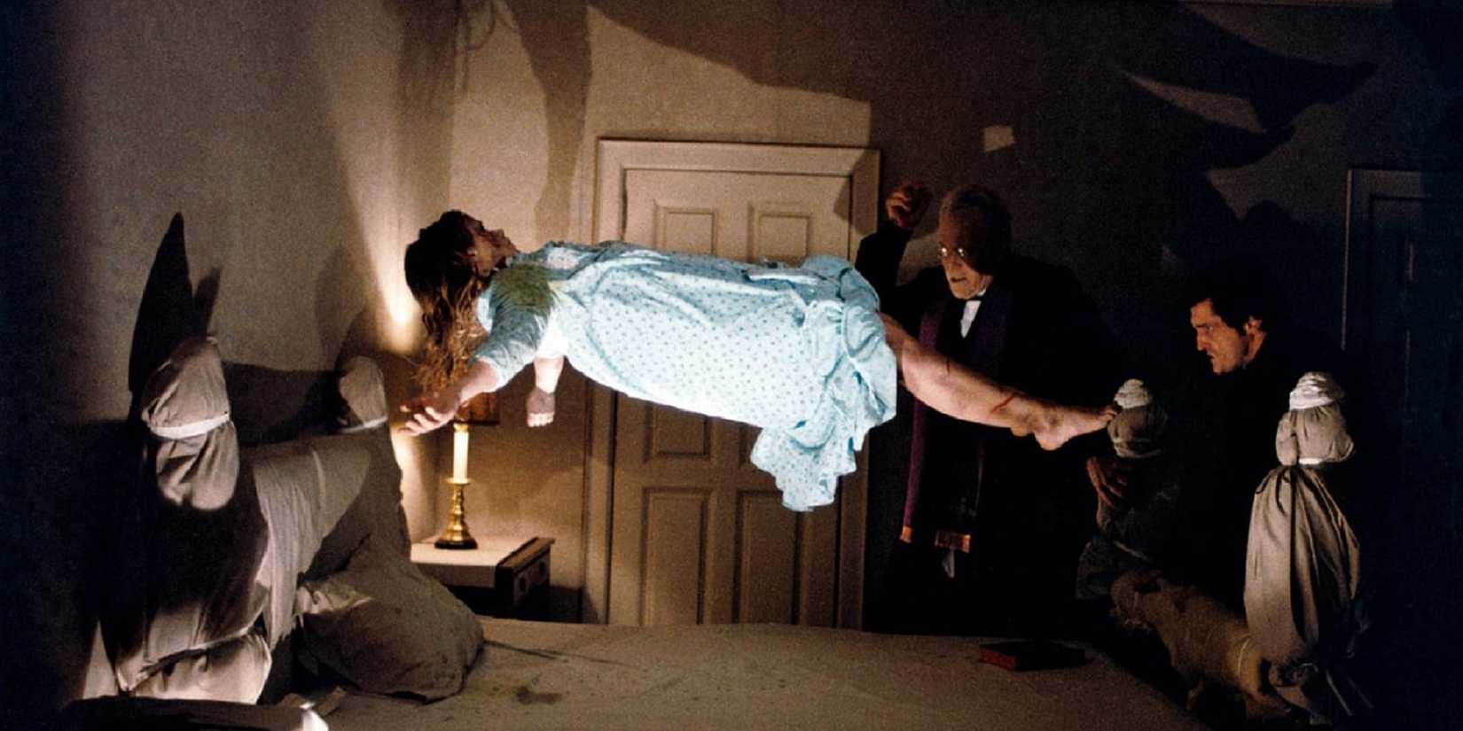 Linda Blair dans L'Exorciste, flottant au-dessus de son lit pendant que deux prêtres observent.