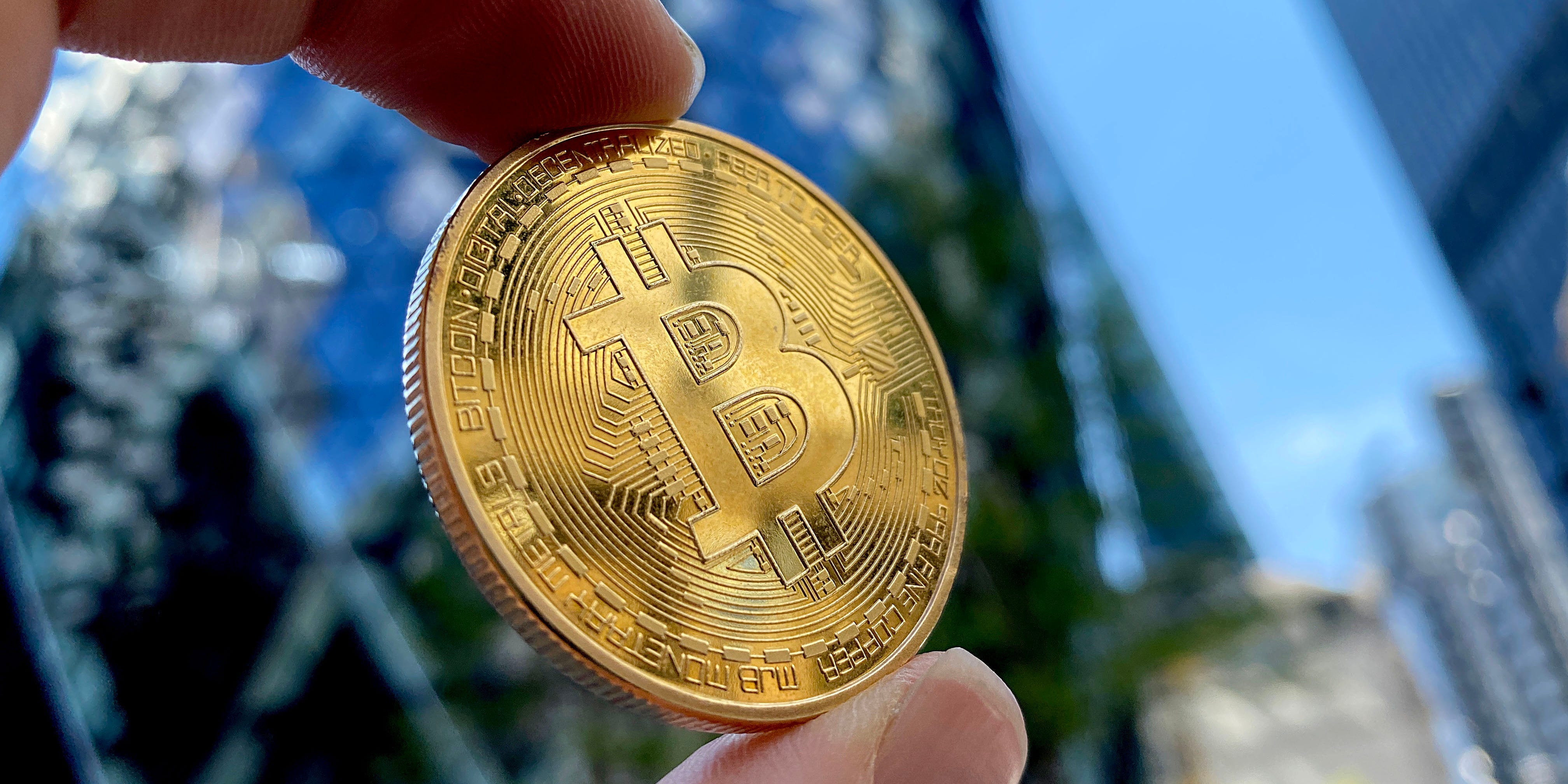 Une main tenant un bitcoin vers le ciel