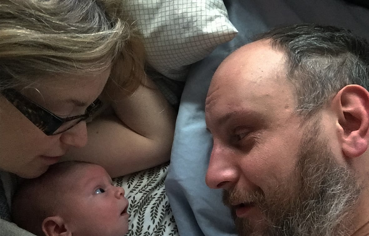Gros plan d'un homme et d'un bébé, avec une femme aux cheveux blonds.
