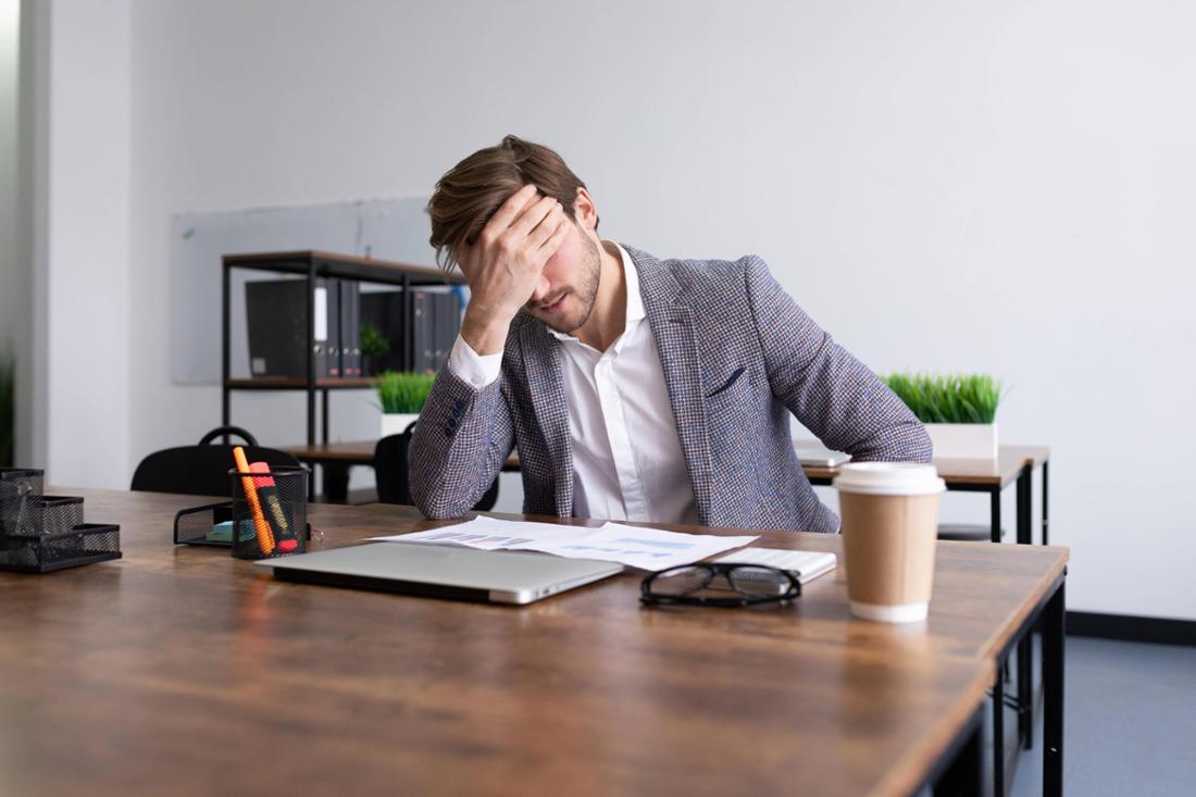 Un homme d'affaires visiblement fatigué dans un bureau.