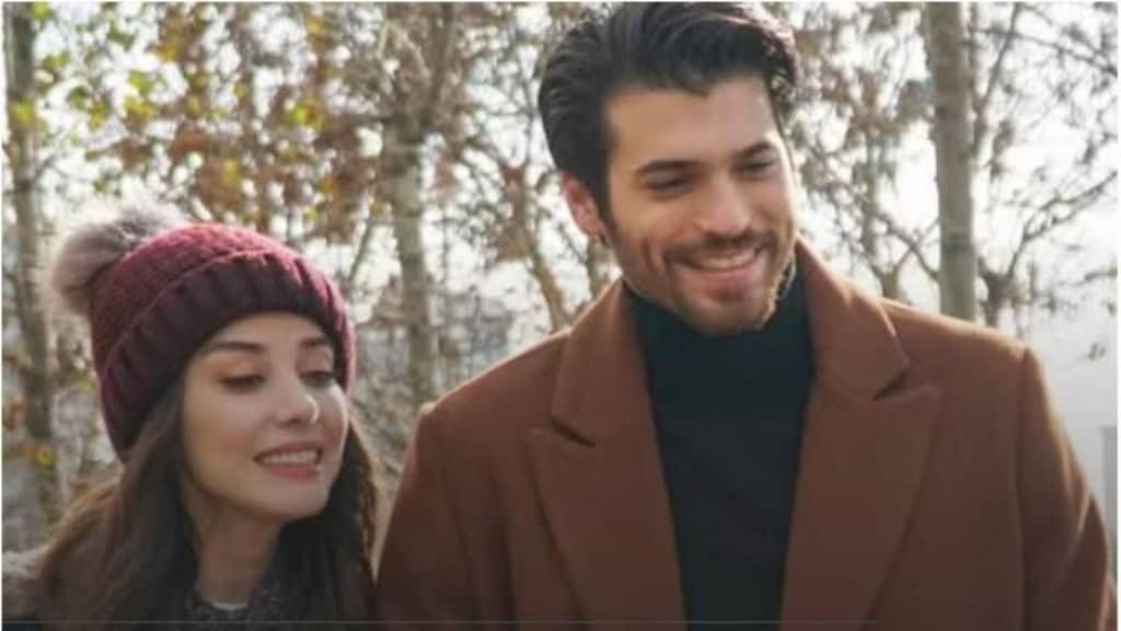 Deux personnages souriants en extérieur, ambiance hivernale sans feuilles aux arbres.