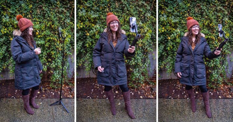 Une femme en manteau d'hiver et bonnet orange se tient à l'extérieur. Elle installe un trépied avec un téléphone puis prend un selfie, souriante, avec de la vigne verte en arrière-plan.