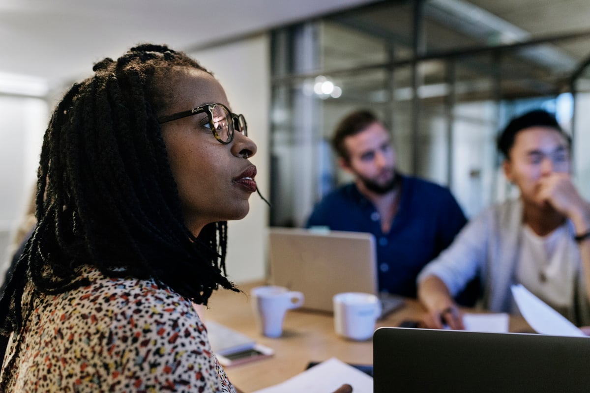 Trois investisseurs discutent autour d'une table avec des ordinateurs portables.