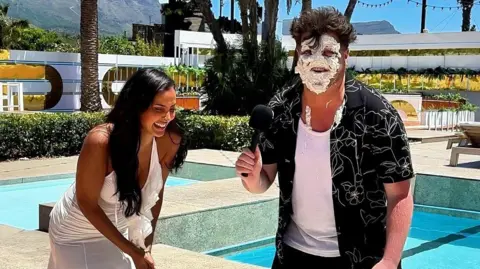 Morgan James avec de la crème sur le visage, riant aux côtés de Maya Jama.