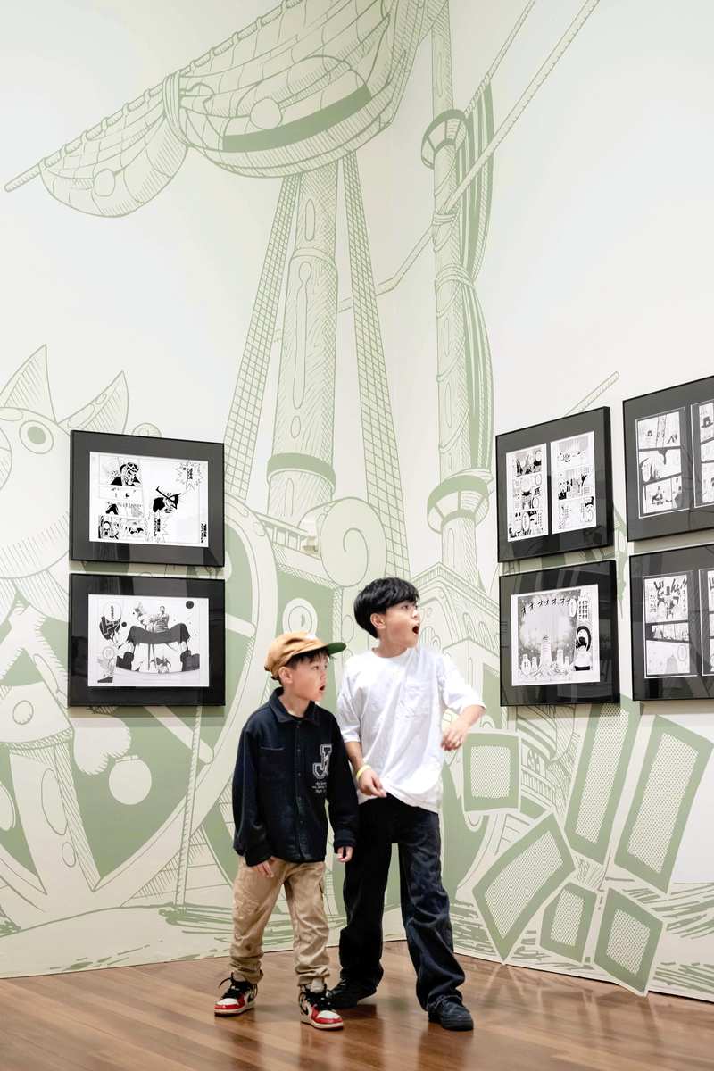 Enfants admirant les œuvres d'Eiichiro Oda