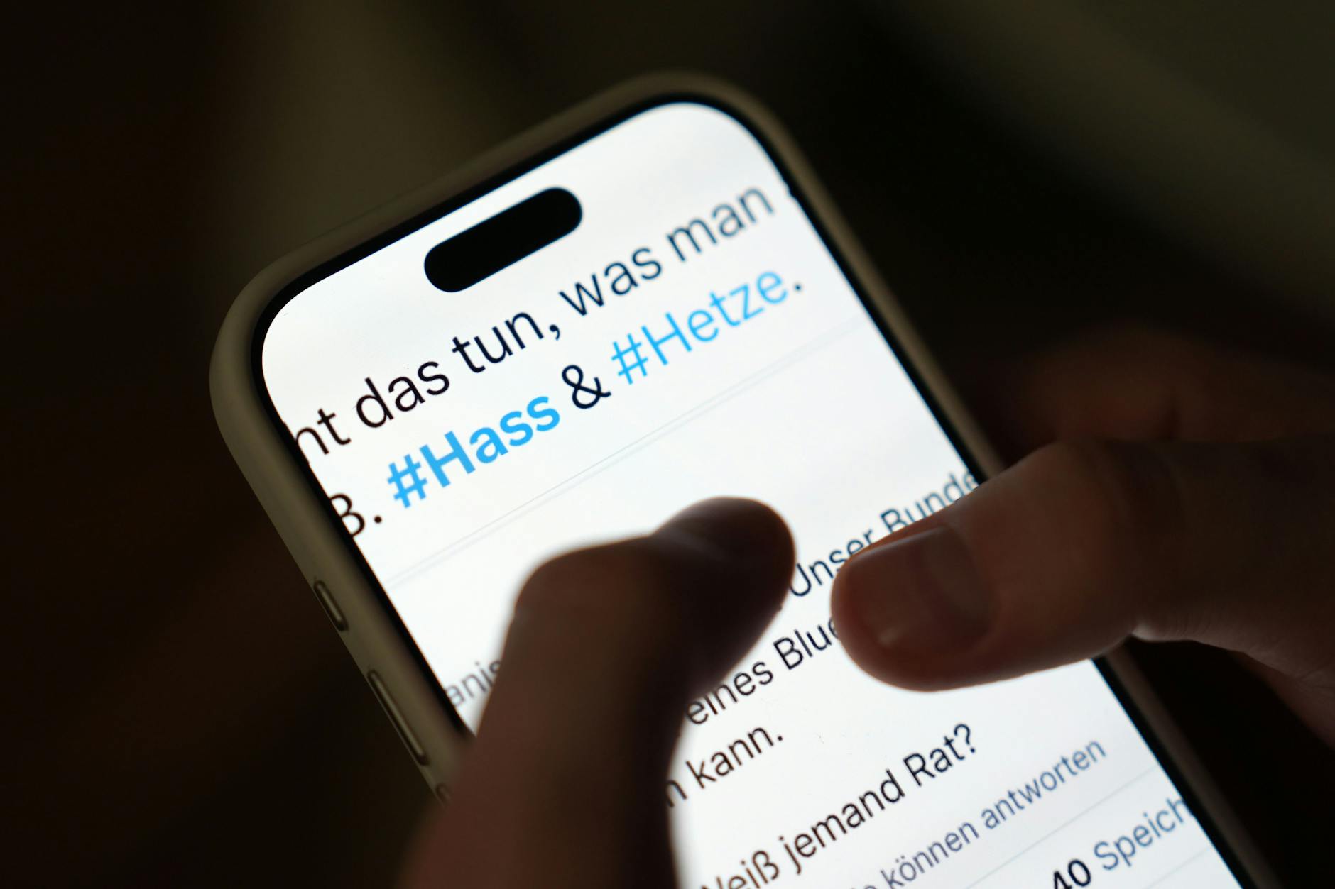 Un smartphone affichant les hashtags #Hass et #Hetze sur un réseau social, témoignant de la violence numérique.