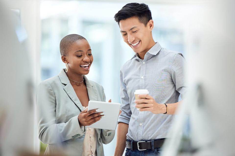 Deux personnes souriant en regardant une tablette.