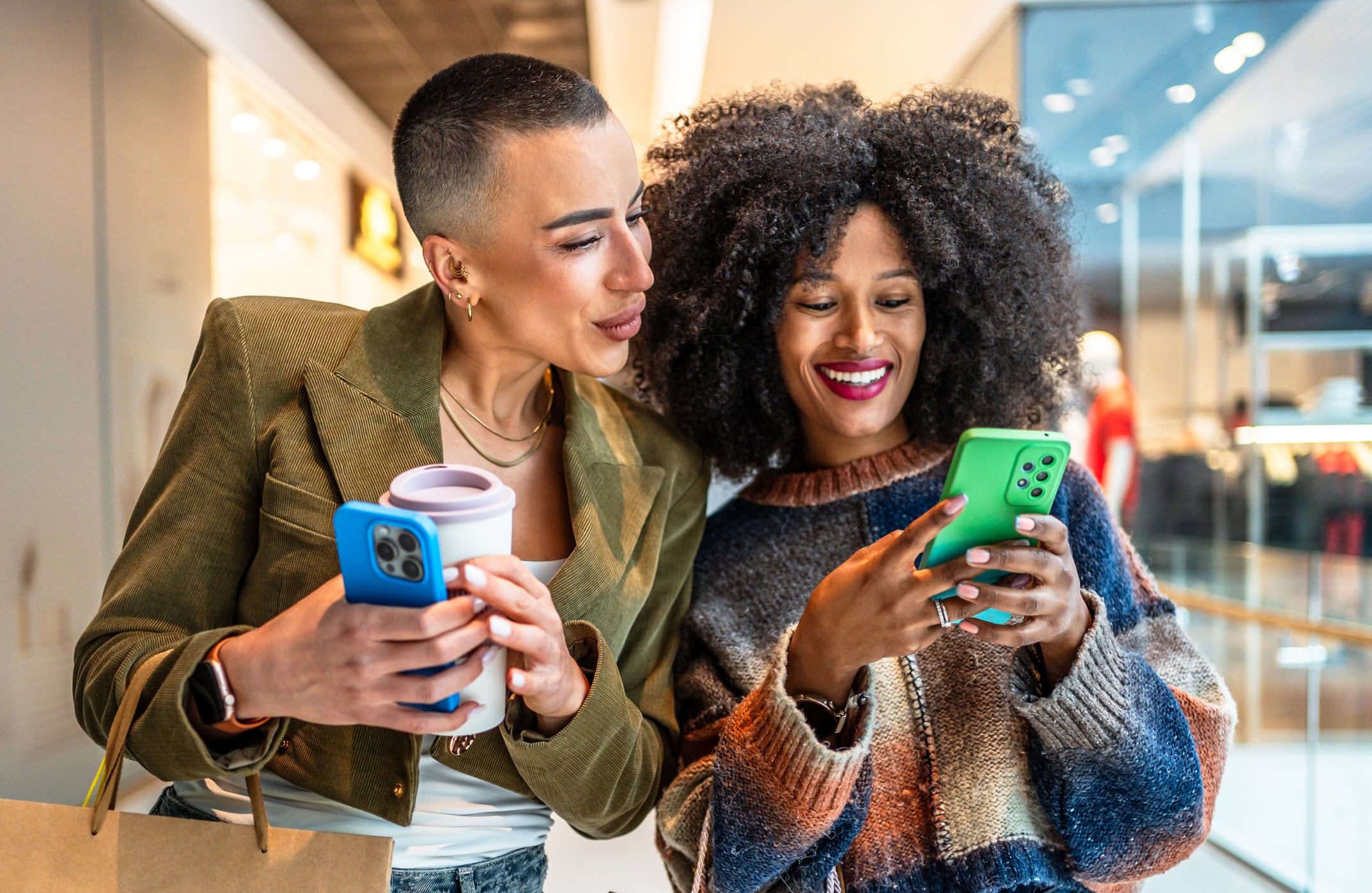 Deux amies s'amusent à faire du shopping dans un centre commercial, partageant des moments tout en dégustant un café.