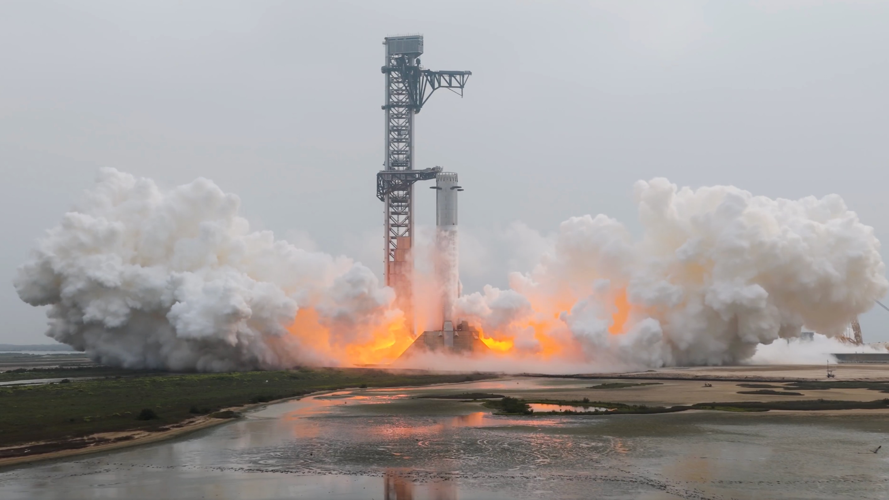 A silver rocket firing engines on the launch pad