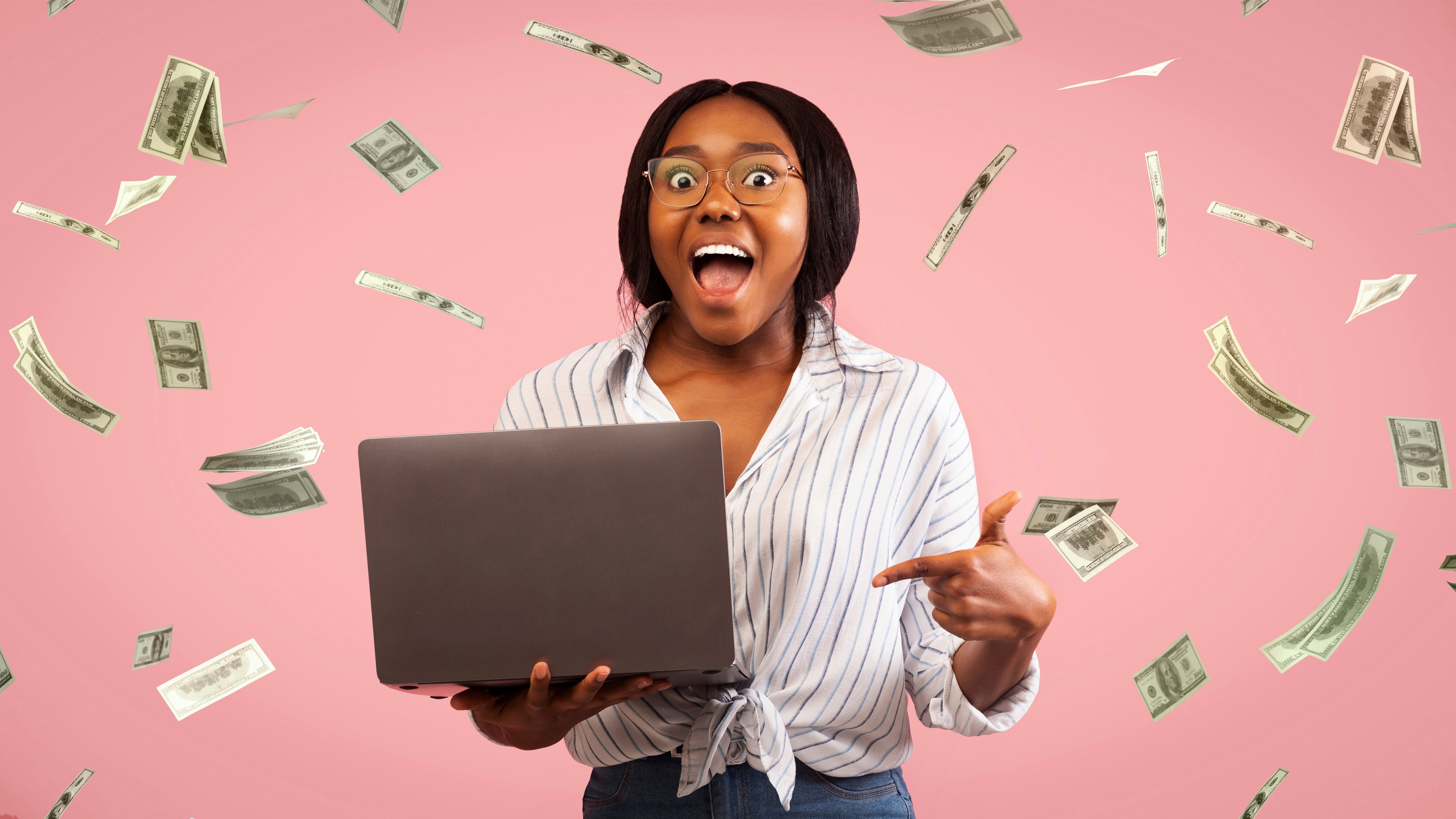 Un investisseur avec un ordinateur portable, entouré de billets de dollar.