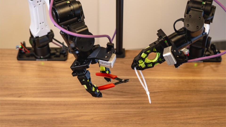 Un robot utilise une pince tandis qu'un autre manipule un collier de câbles : Les robots ENPIRE ont été formés à des tâches de gestion de câbles PC. (© Nvidia Gear Lab)