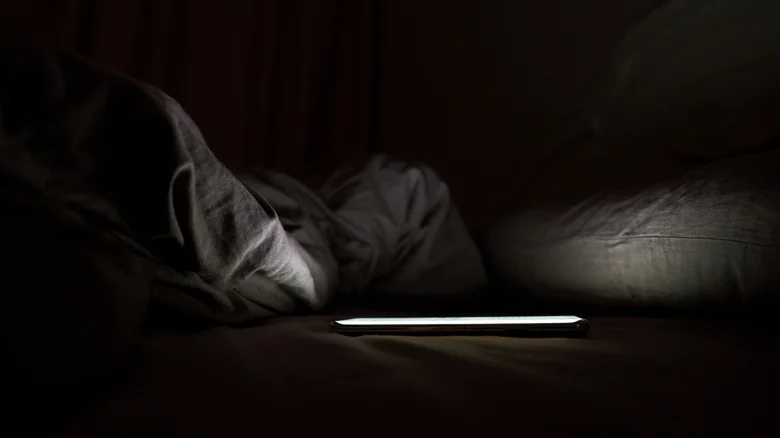Un téléphone posé sur un lit dans une pièce sombre
