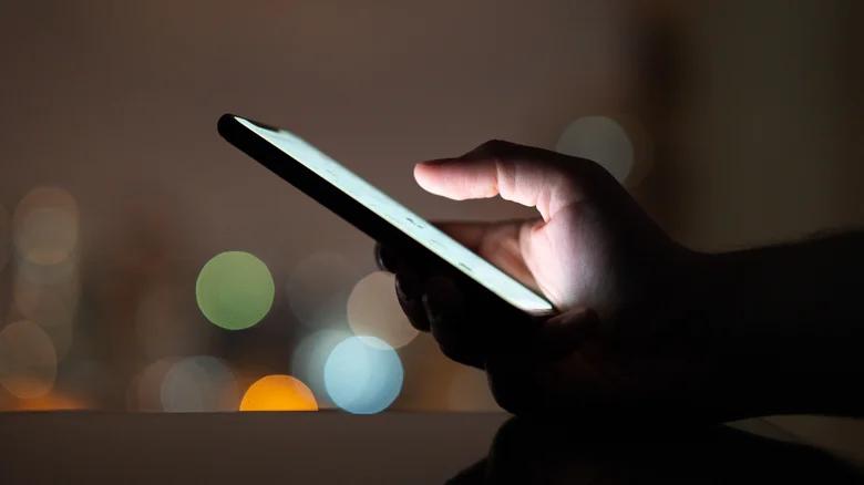 Une personne utilisant un téléphone le soir