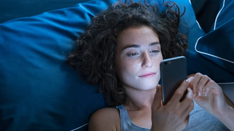 Une femme utilisant un téléphone au lit