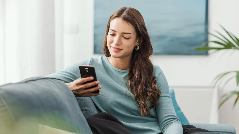 Une femme utilisant un téléphone sur un canapé