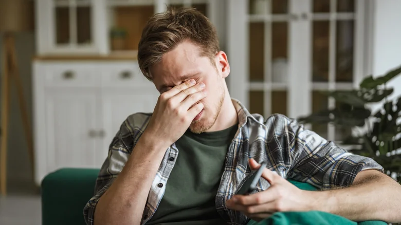 Un homme se frottant les yeux en raison de la fatigue oculaire