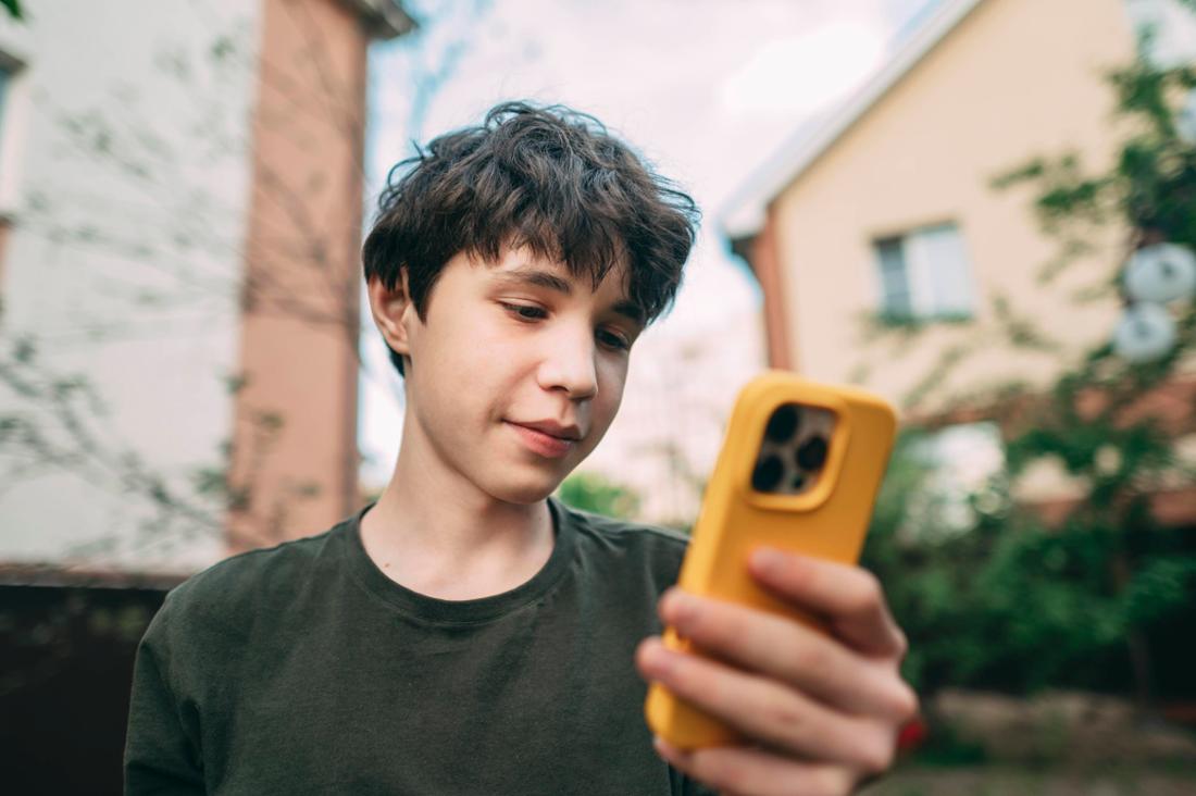 Un adolescent tenant un téléphone jaune.