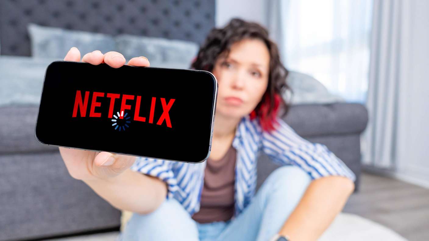 Une femme tenant un smartphone avec le logo de Netflix.