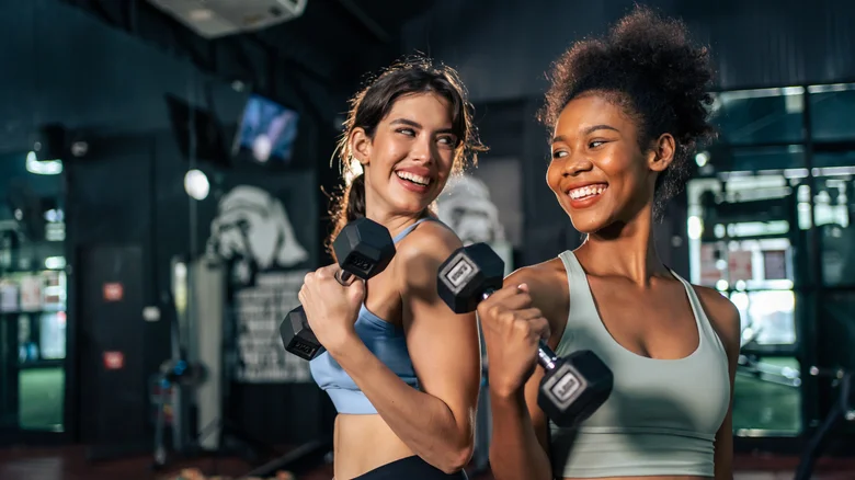 Deux femmes levant des haltères à la salle de gym.