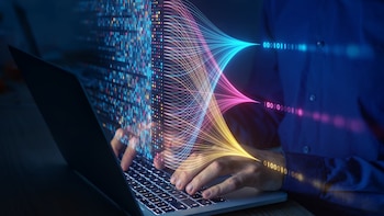 Personne tape sur un clavier avec des lignes lumineuses et un code binaire