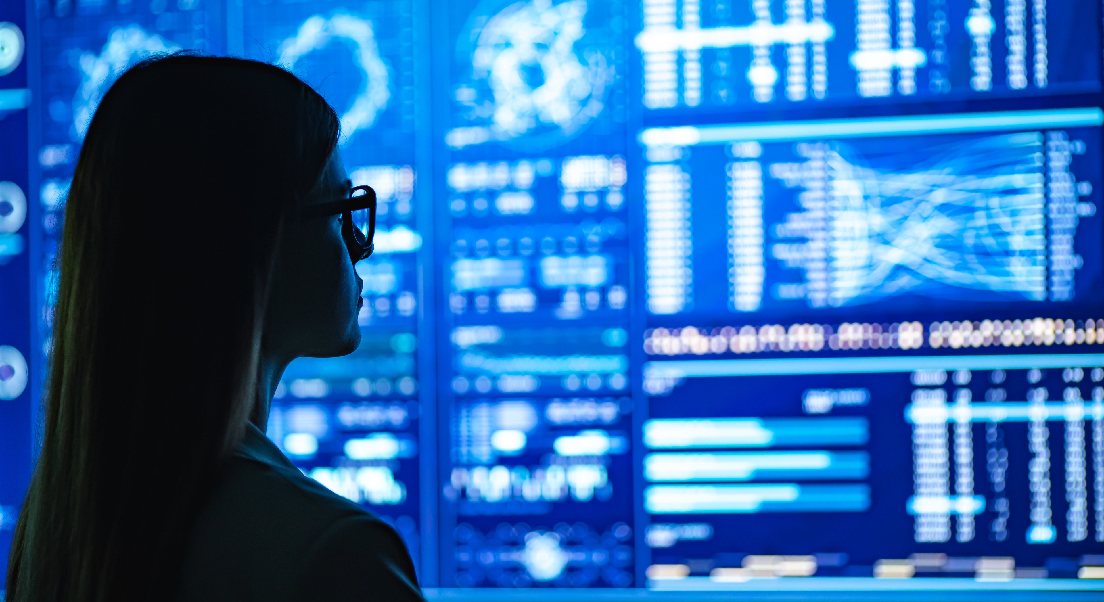 Person analyzing wall of trading screens.