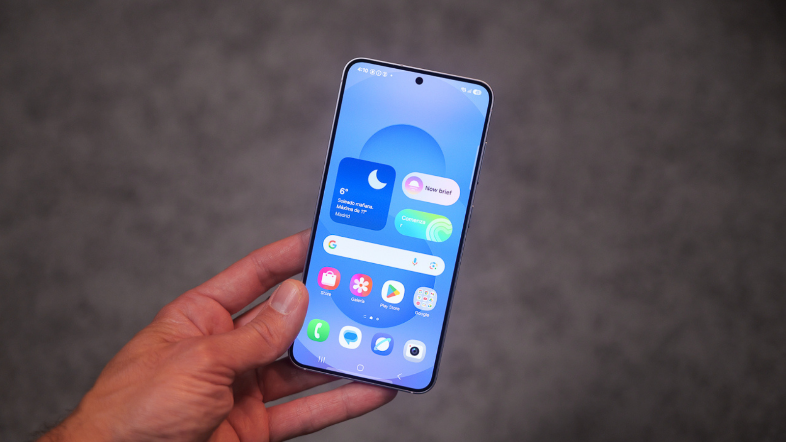 Premier plan du Samsung Galaxy S25 dans une main, montrant l'interface d'accueil avec des widgets et des applications.