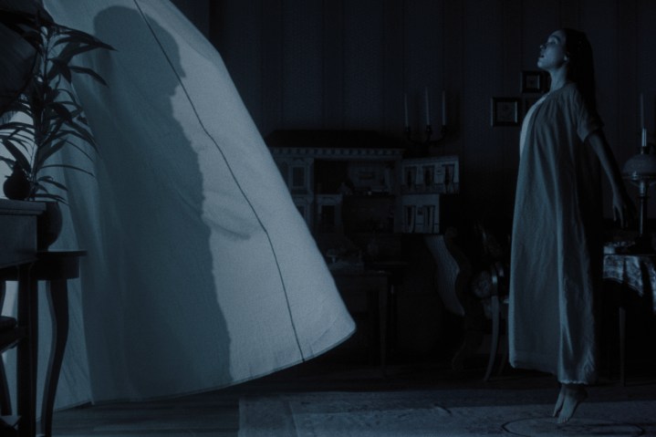 Lily-Rose Depp flotte devant des rideaux de fenêtre flottants dans "Nosferatu."