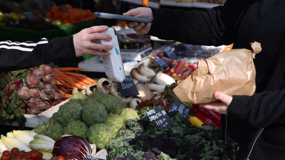 Un client paie avec son téléphone au marché.