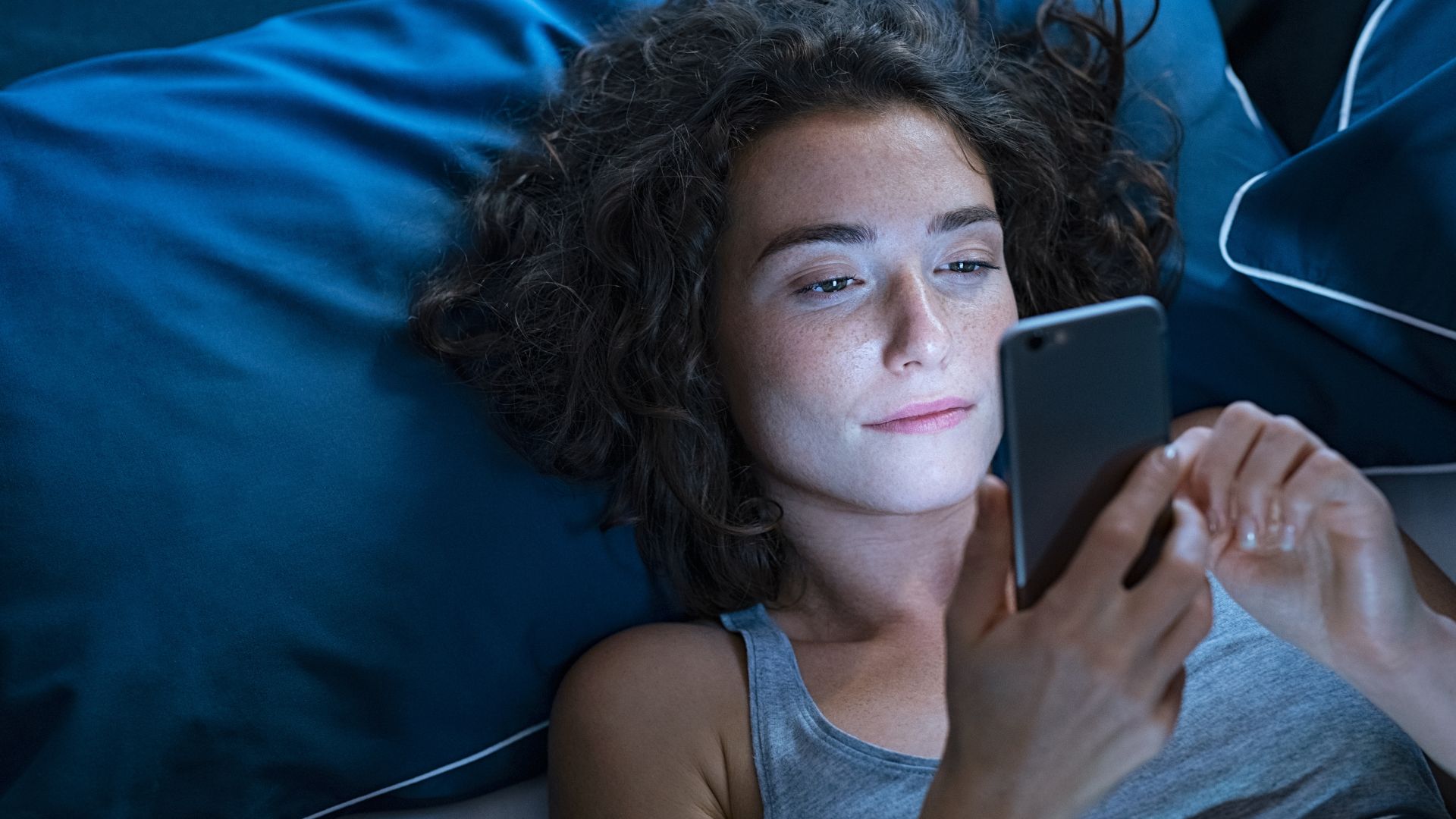 Femme regardant son téléphone au lit
