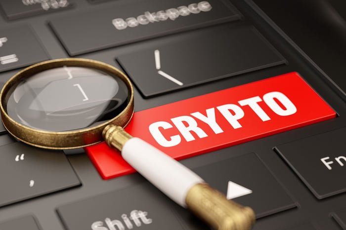Bouton crypto rouge sur un clavier avec une loupe
