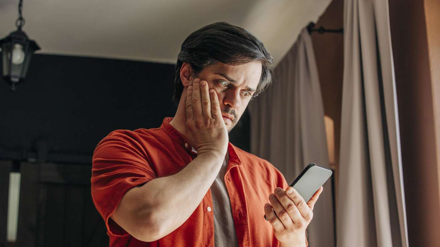 Un homme regarde choqué son téléphone.