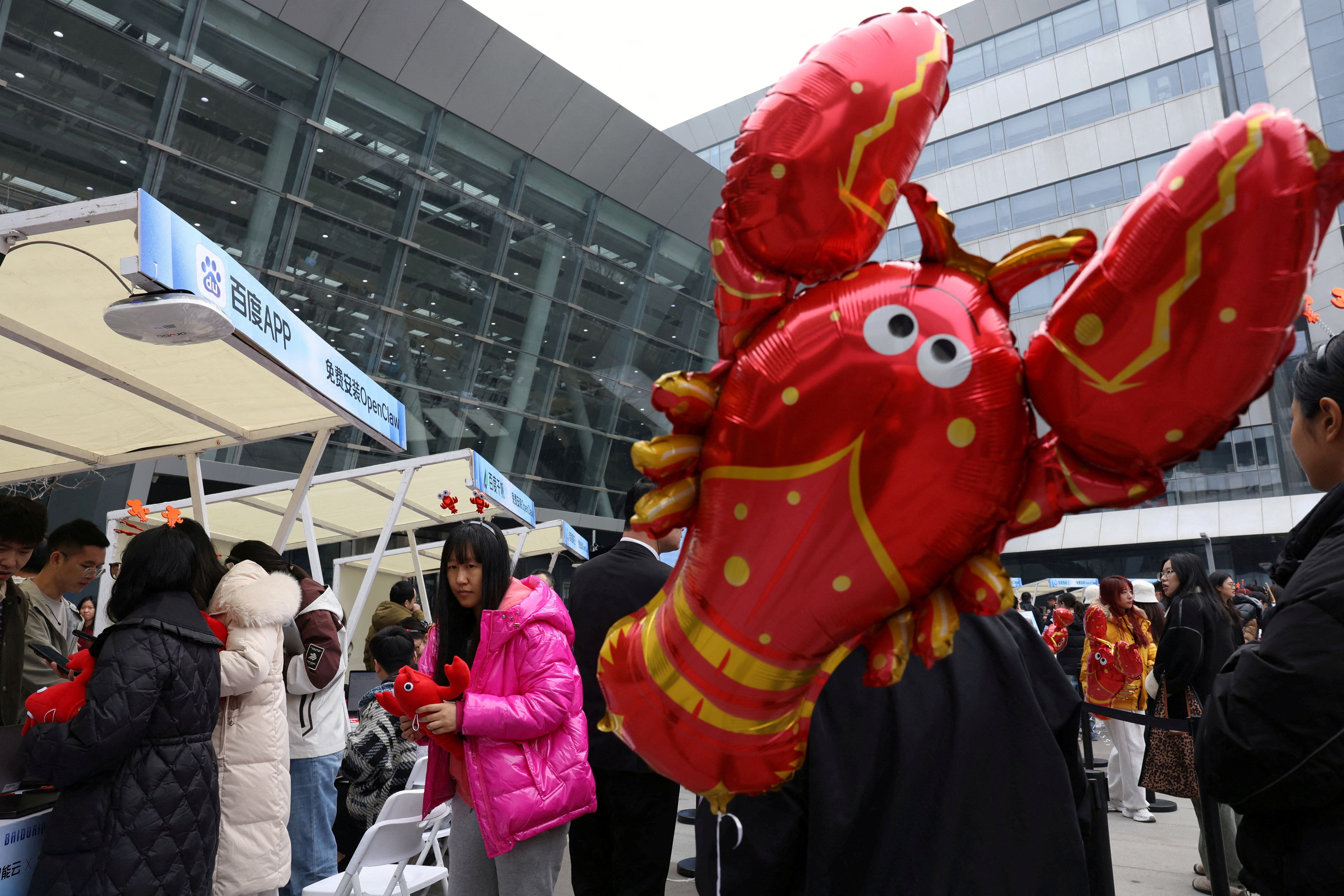Des participants se tiennent en ligne près d'un ballon en forme d'homard pour configurer et installer OpenClaw devant les bureaux de Baidu à Pékin.