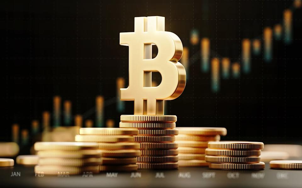 Logo Bitcoin sur des pièces d'or avec un graphique en arrière-plan.
