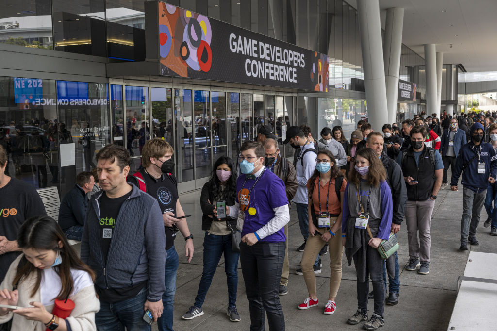 Des participants, beaucoup portant des masques, attendent en ligne à l'extérieur de la Game Developers Conference 2022