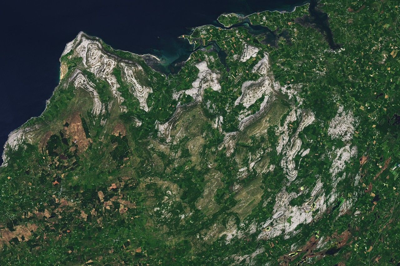 Vue satellite du Burren en Irlande, montrant des collines grises en calcaire disposées en bandes concentriques entourées de terres agricoles verdoyantes.