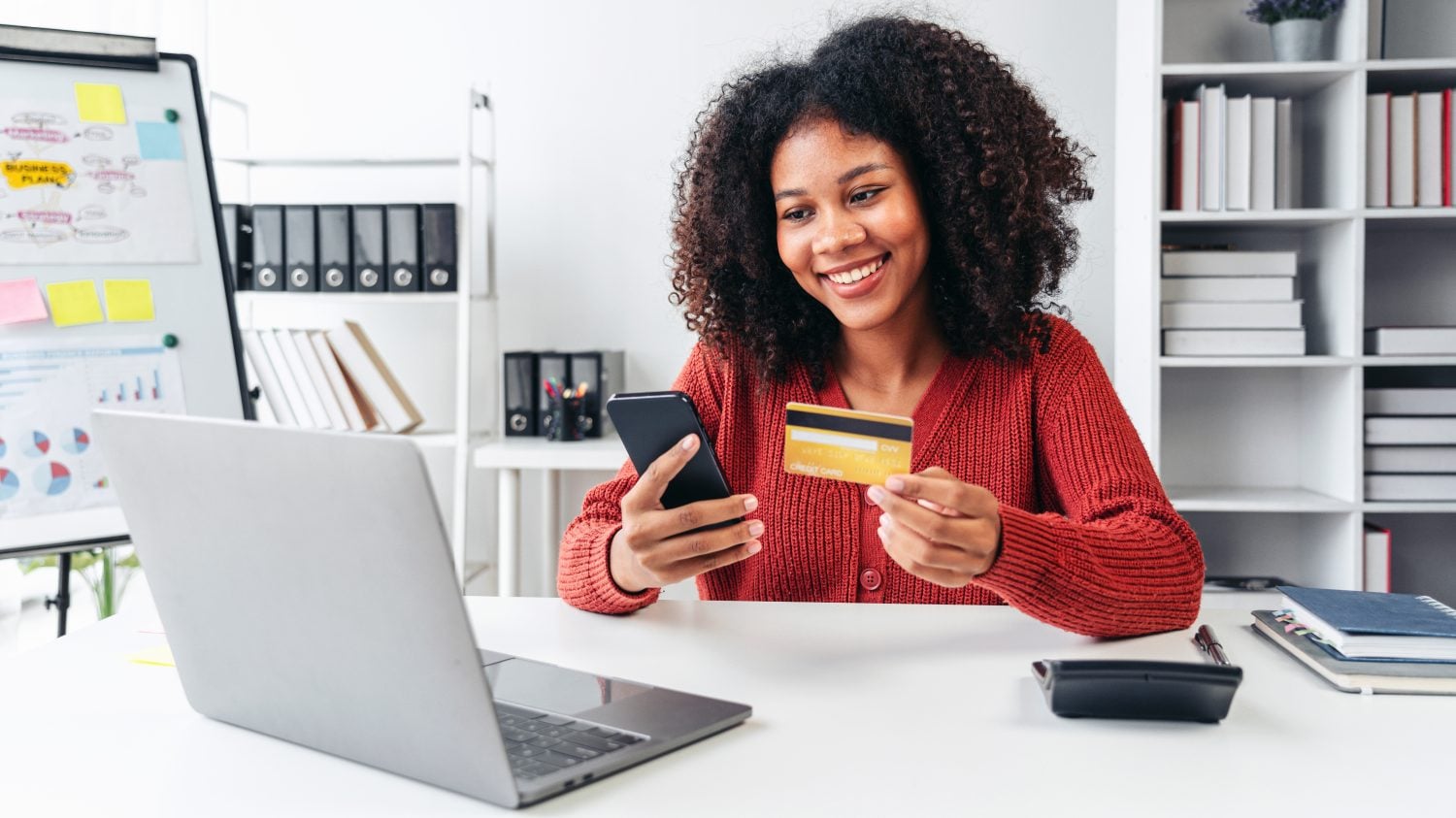 Une femme sourit en utilisant son téléphone portable pour effectuer un paiement