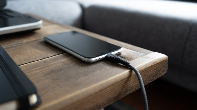 Smartphone branché à un chargeur sur une table de nuit.