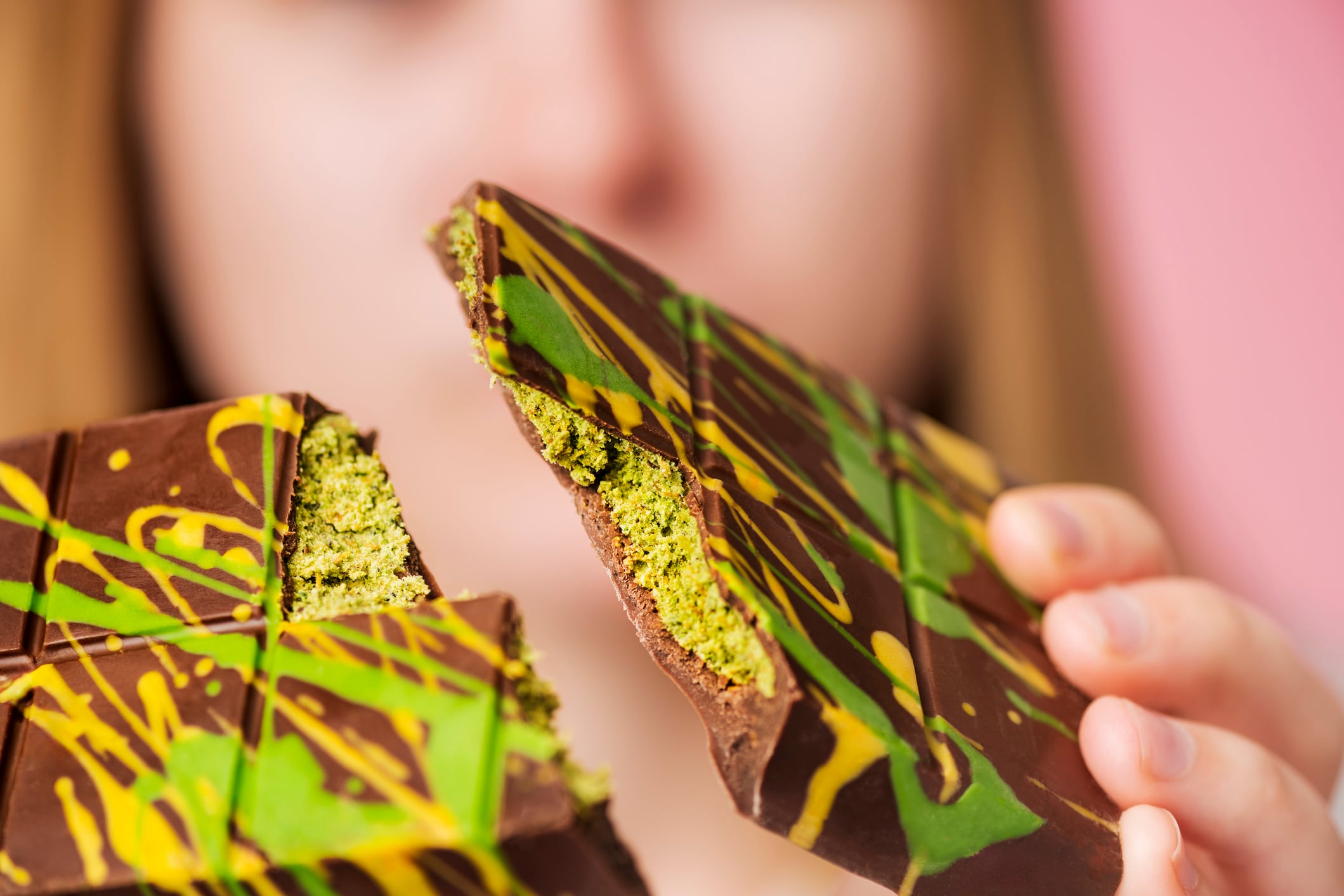 Une jeune femme tient une barre de chocolat de Dubaï que l'on a coupée en deux, mettant en avant ses ingrédients.